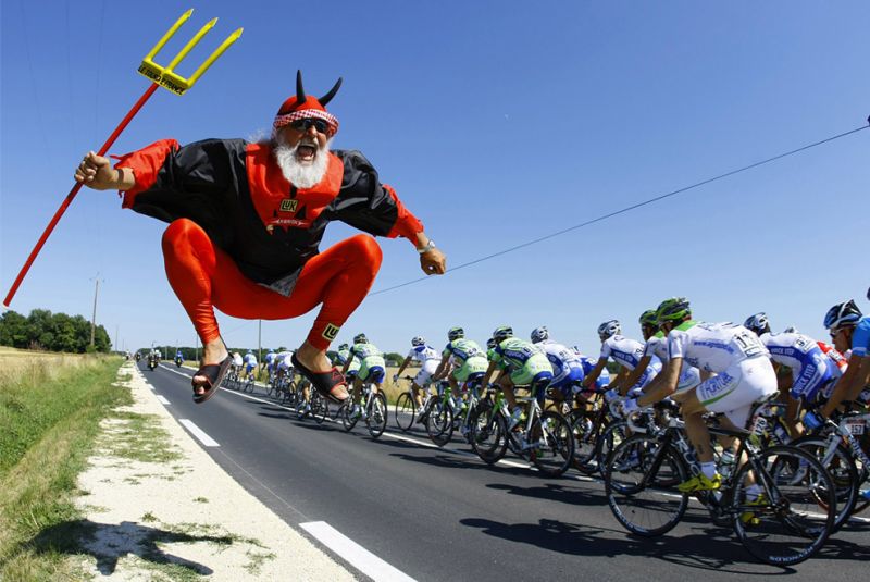TF 0030 A spectator known as Didi dressed as a deviljumps beside a pack of riders during the stage